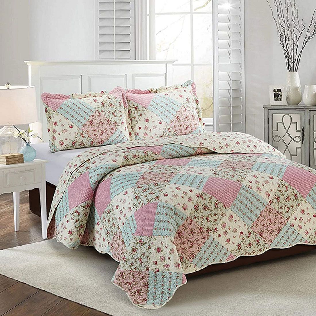 A cosy bedroom with a matching pink pillowcase and bedspread in a patchwork design.