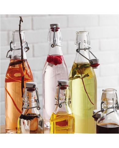 A variety of glass bottles filled with infused beverages, featuring fruits, herbs, and spices.