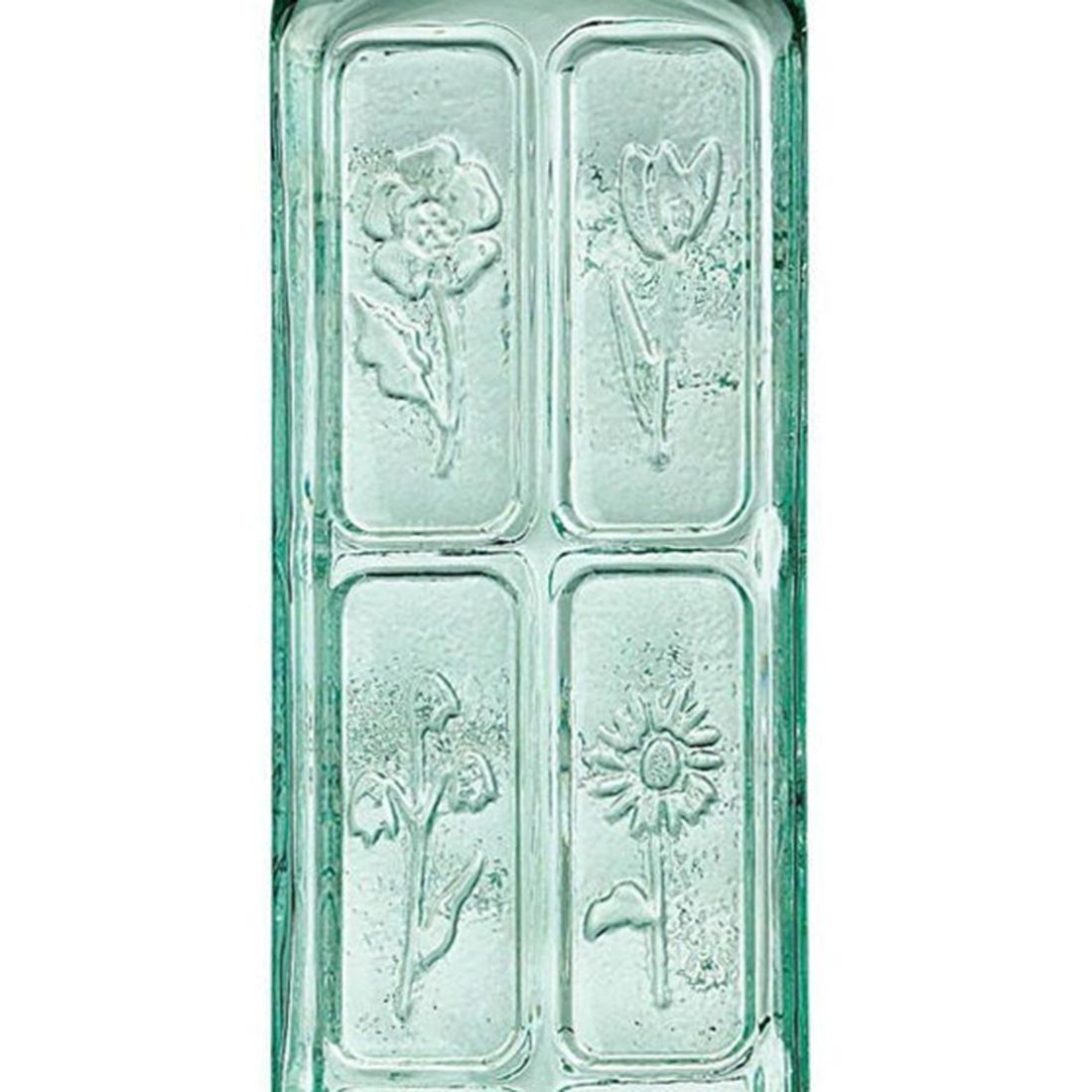 A close up of the floral engravings on the green-tinted glass oil bottle.