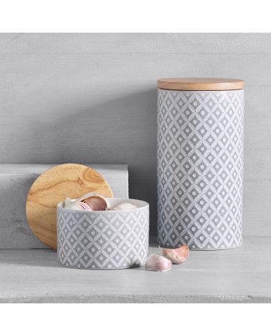 Twee exemplaren van de grijze opbergpot, de ene open met knoflookteentjes, de andere met een houten deksel. Twee exemplaren van de grijze opbergpot, de ene open met knoflookteentjes, de andere met een houten deksel.