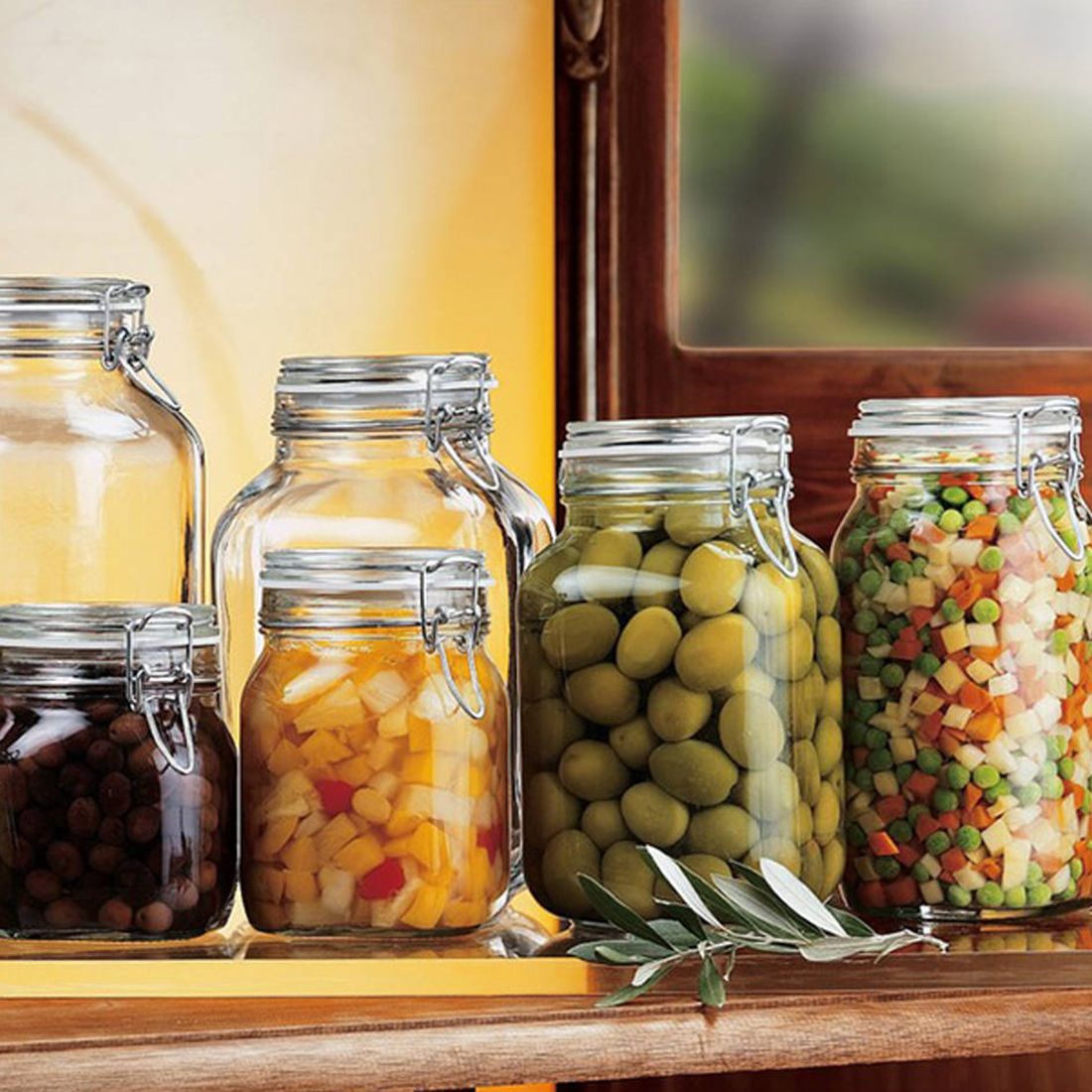 A collection of glass preserving jars filled with olives, colourful diced vegetables, and assorted fruits. A collection of glass preserving jars filled with olives, colourful diced vegetables, and assorted fruits.