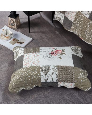 A beige patchwork pillowcase in Vintage Rose patterns rests on a textured grey floor.