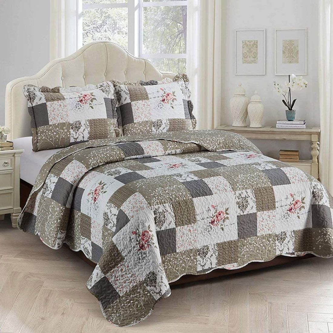 Kussensloop beige an patchwork sprei met bloemmotief op een bed in een lichte gedecoreerde kamer.