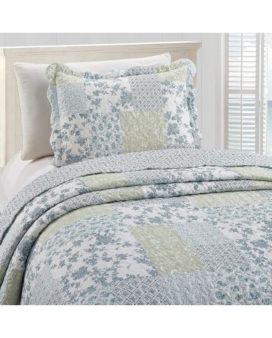 Een kussensloop wit en blauw met bijpassende sprei op een knus bed bij het raam. Een kussensloop wit en blauw met bijpassende sprei op een knus bed bij het raam.