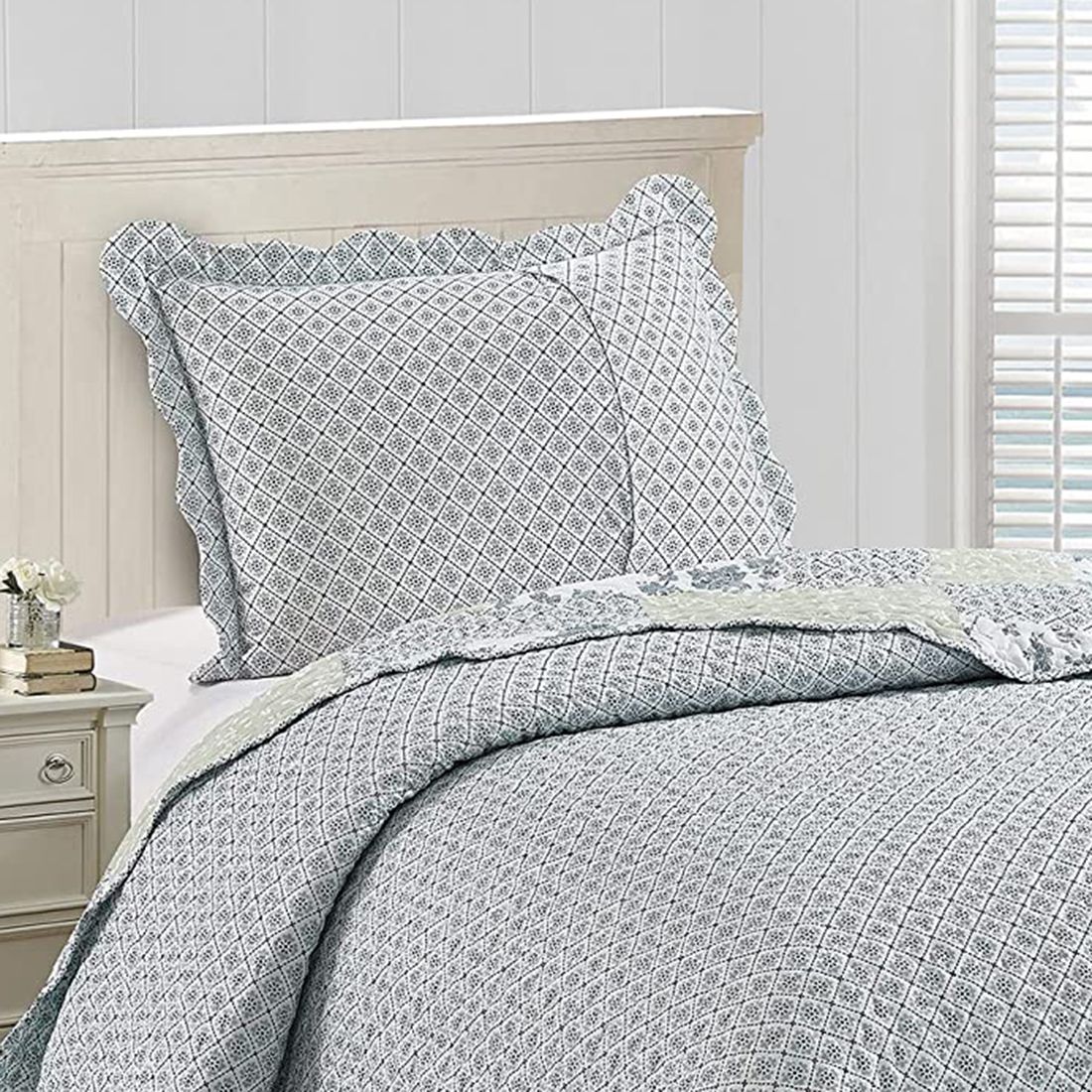 Het omkeerbare ontwerp van de kussensloop wit en blauw, een kleine bloemenprint, op een netjes opgemaakt bed.