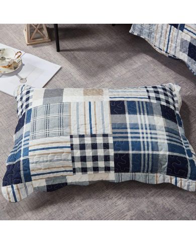 A blue patchwork pillowcase in Blue Loft patterns rests on a textured grey floor.