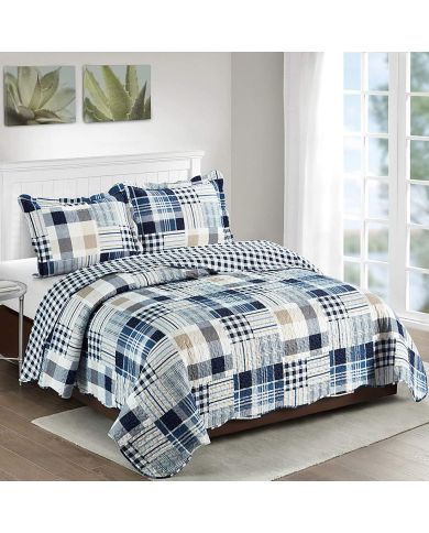 A patchwork quilt in shades of blue and white on a bed with matching pillows.