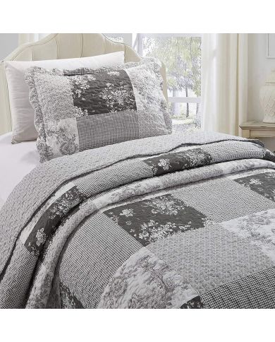 Een grijze kussensloop met bijpassende sprei op een knus bed bij het raam. Een grijze kussensloop met bijpassende sprei op een knus bed bij het raam.