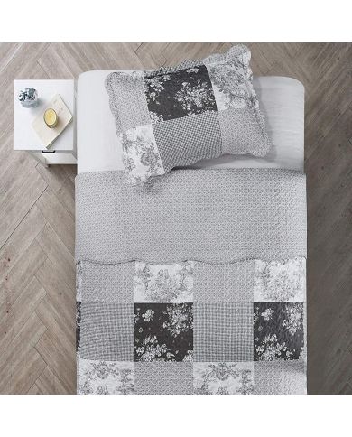 Top view of a patchwork pillowcase on a bed, complemented by a matching quilt.