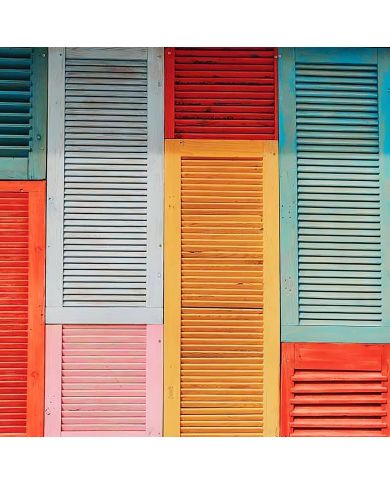 Colourful wooden shutters in various colours create a vibrant patchwork pattern on a wall. Colourful wooden shutters in various colours create a vibrant patchwork pattern on a wall.