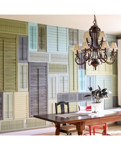 Een levendige muur van kleurrijke louvre shutters en een elegante kroonluchter boven een houten tafel. Een levendige muur van kleurrijke louvre shutters en een elegante kroonluchter boven een houten tafel.