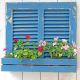 An upcycled planter made from bluewash shutters, adorned with vibrant pink and white flowers.