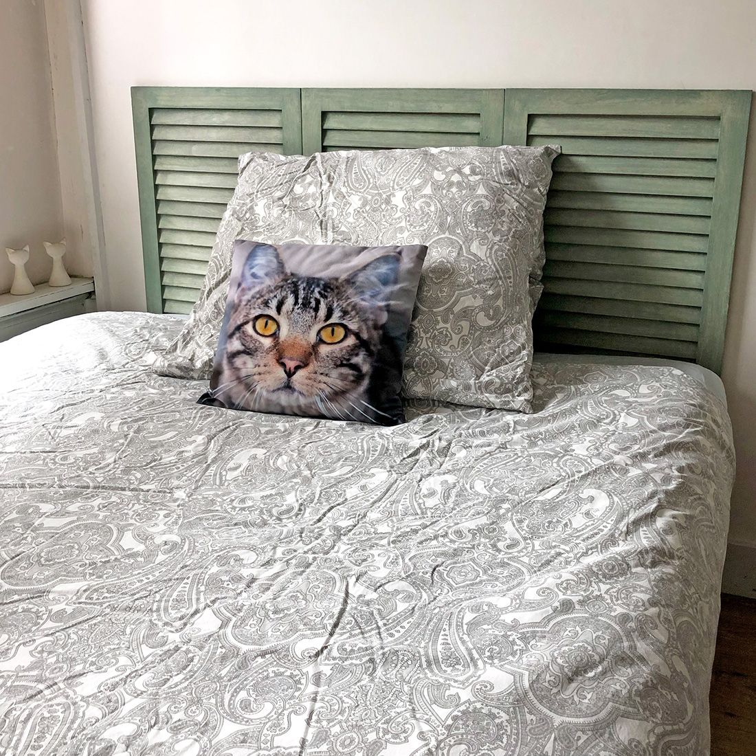 Gezellige slaapkamer met een upcycled witte shutter - hoofdbord, geaccentueerd door een kussen met kattengezicht. Gezellige slaapkamer met een upcycled witte shutter - hoofdbord, geaccentueerd door een kussen met kattengezicht.