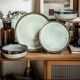 A collection of bohemian dinner plates in earthy tones, including plates and a bowl, displayed on a wooden shelf.