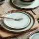 A set of elegant bohemian dinner plates with a reactive glaze, on a rustic wooden table.