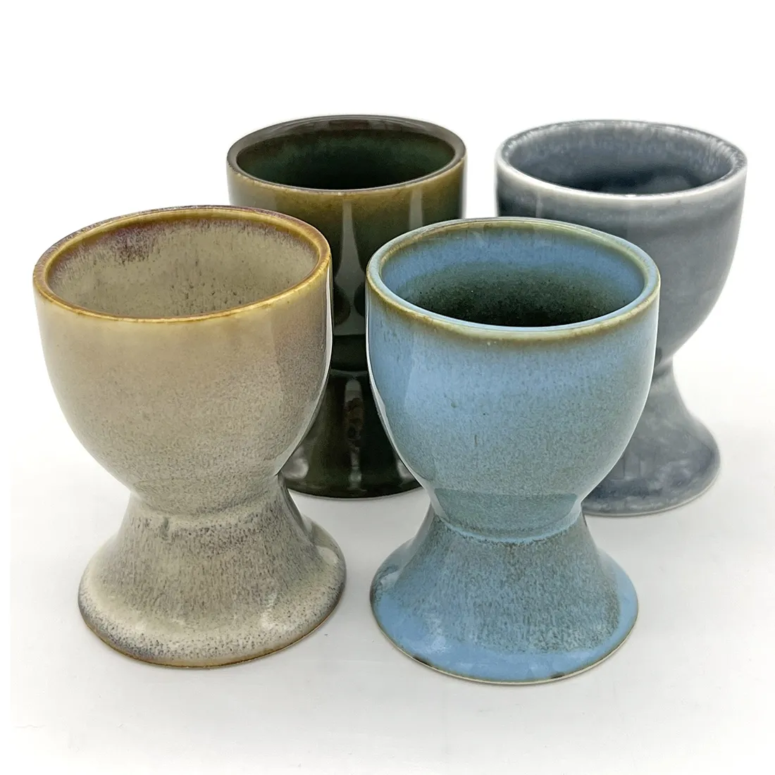 Four assorted ceramic egg cups with a reactive glaze finish. Four assorted ceramic egg cups with a reactive glaze finish.