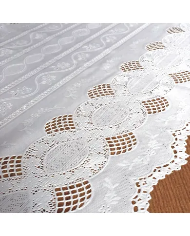 Close up detail of a white table runner made from vinyl with lace details and scalloped edges.