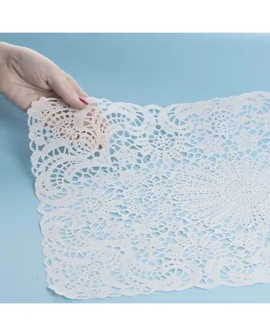 A hand holds a lace vinyl placemat, highlighting the laser-cut lace patterns.