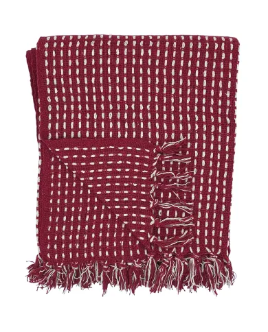 Een gevouwen rode plaid met een wit steekpatroon en kwastjes aan de randen.