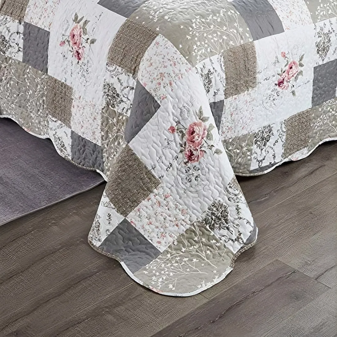 Een patchwork bedsprei beige en wit gekleurd, met bloemmotieven, vermicellistiksels en geschulpte randen.