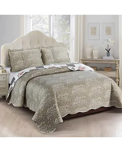 A cosy quilt with floral and patchwork designs in beige, paired with a matching pillow on a neatly made bed.