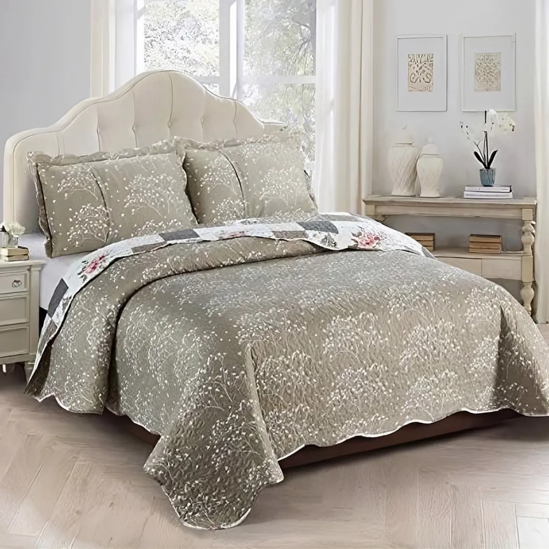 Een gezellige bedsprei beige en wit gekleurd, met bloemen- en patchworkmotieven, daarbij een bijpassend kussen.