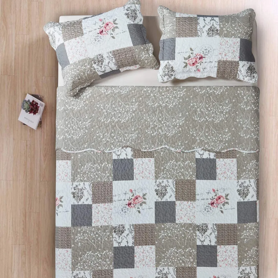 Bedsprei beige en wit gekleurd, met een gebloemd patchworkmotief, daarrbij een bijpassende sierkussens.