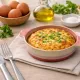 A round oven dish filled with a Spanish omelette, alongside a bowl of eggs.