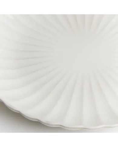 Close-up van een van de witte dinerborden met een subtiel geribbeld patroon en een geschulpte rand.