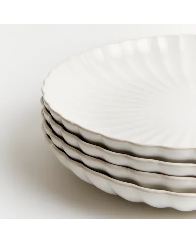 Stack of four white dinner plates with subtle ridged pattern and scalloped edge.