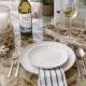 White dinner plate setting, with silverware, a bottle and glass of white wine.