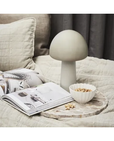 A dessert bowl with nuts sits on a marble tray beside a mushroom lamp.
