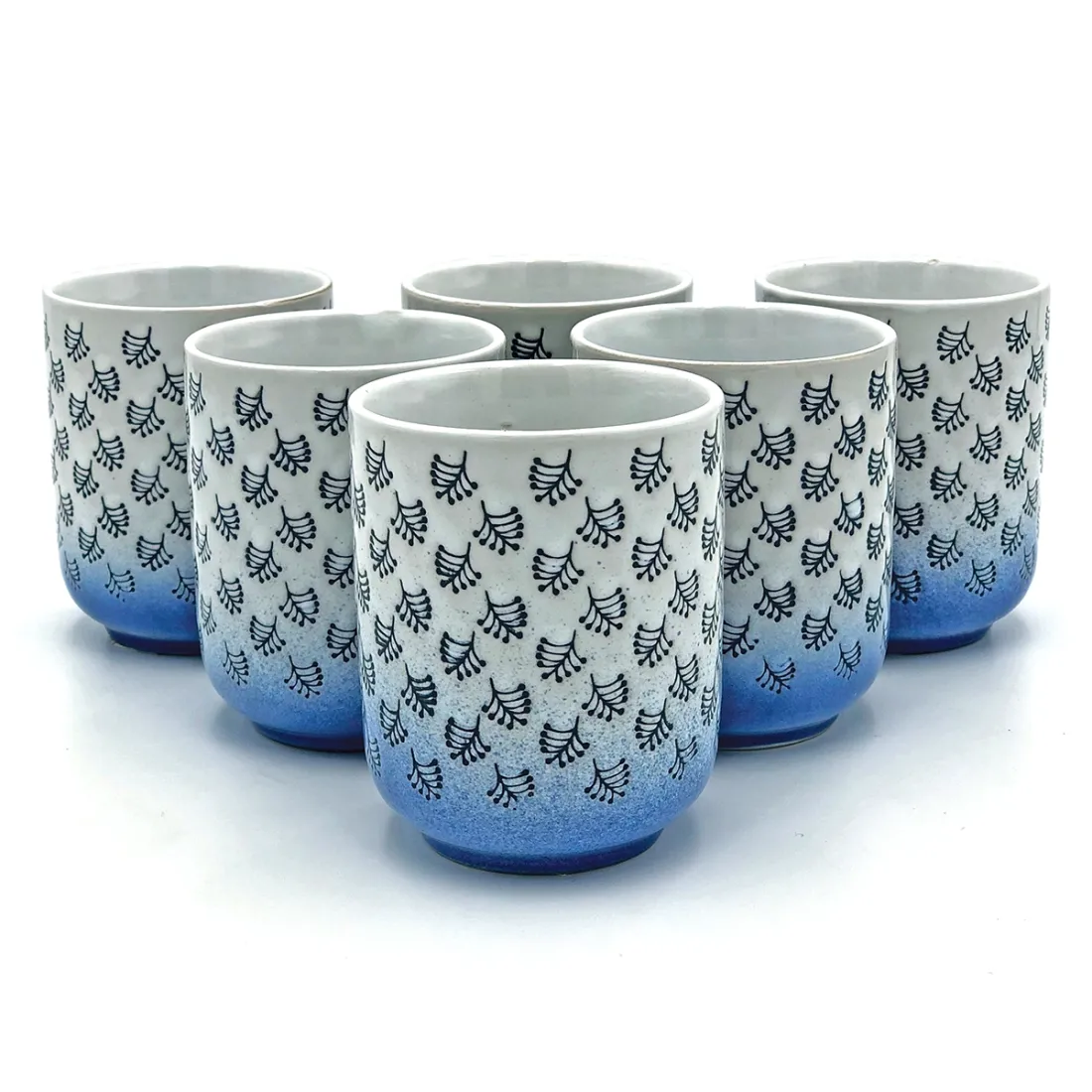 A collection of six white & blue mugs with dark blue leaf patterns and a blue gradient at the bottom.