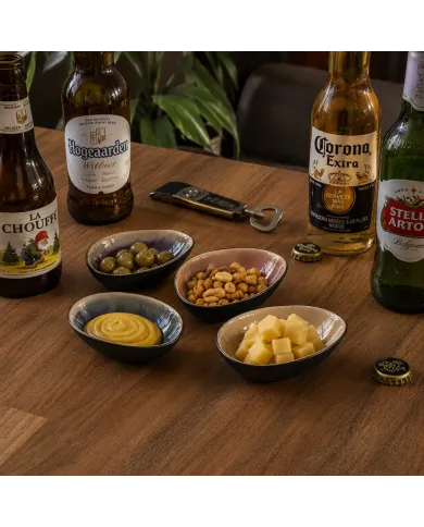 Borrelschaaltjes met olijven, noten, mosterd en kaas, vergezeld van flesjes bier.