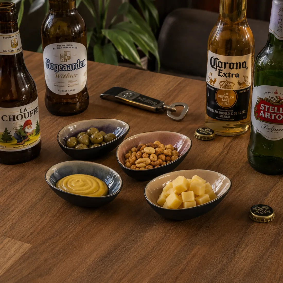 Borrelschaaltjes met olijven, noten, mosterd en kaas, vergezeld van flesjes bier.