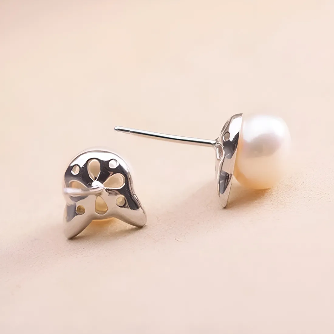Close-up of a pair of silver cat stud earrings with white pearl centers.