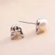 Close-up of a pair of silver cat stud earrings with white pearl centers.