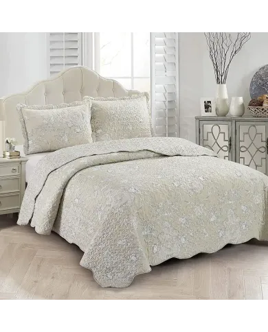 Elegante beige bedsprei met subtiele bloemenprint, geschulpte randen en bijpassende kussenslopen op een knus bed.