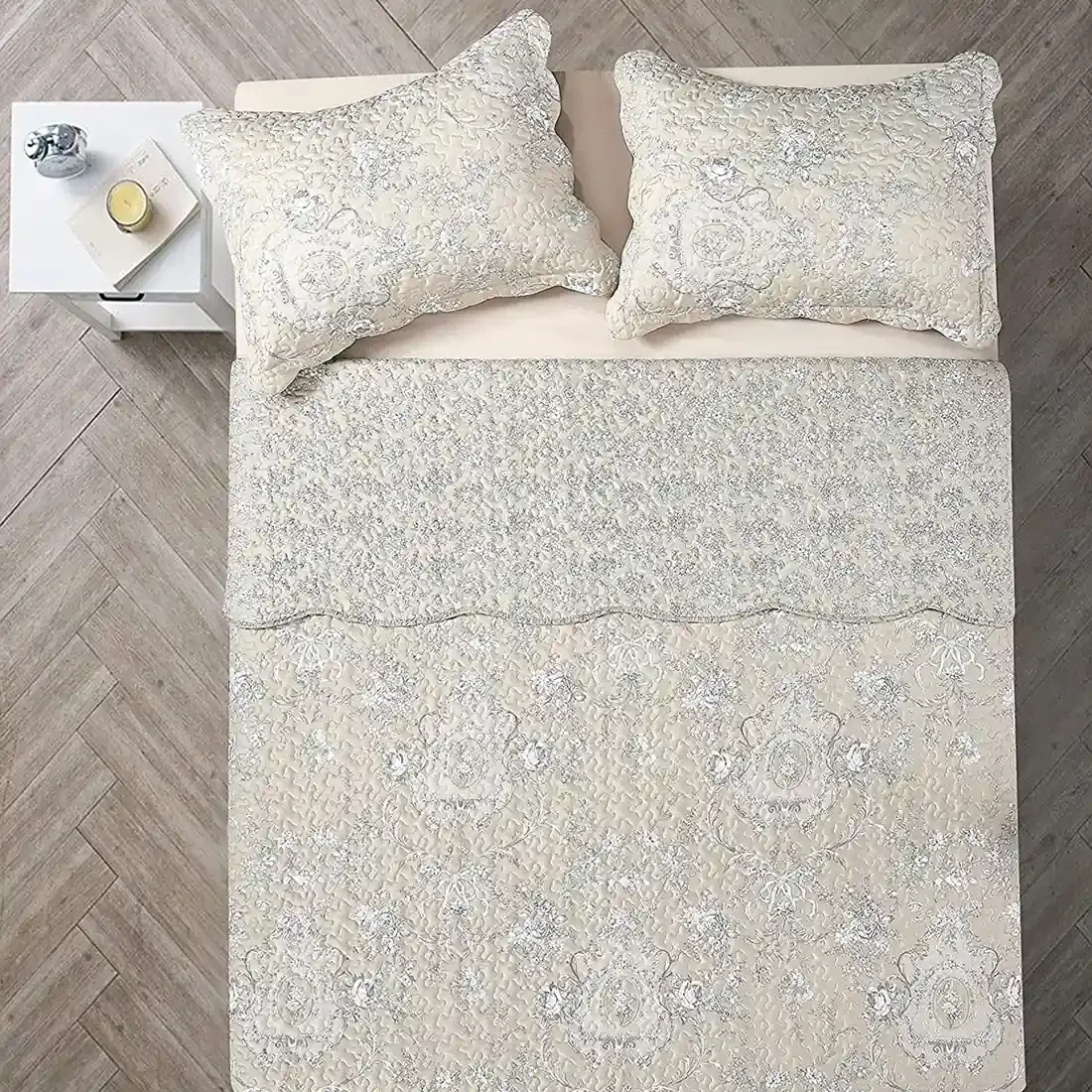 Bovenaanzicht van een beige bedsprei op een bed, aangevuld met bijpassende sierkussens.