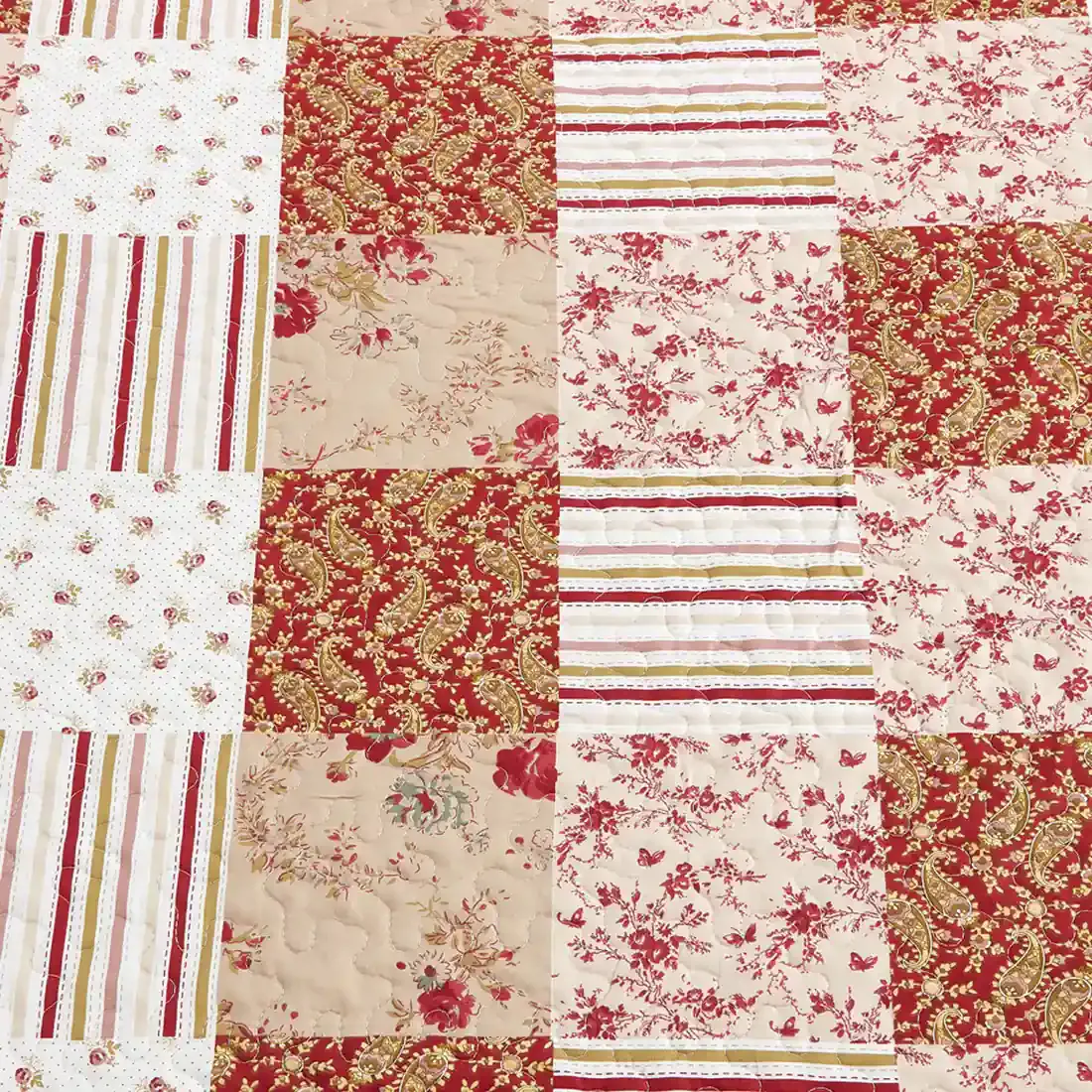 Close-up van een roze bedsprei met een symfonie van gedempt roze en cranberry vlakken.