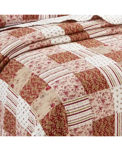 Close-up of a quilt, showcasing a symphony of muted pinks and cranberry tiles.