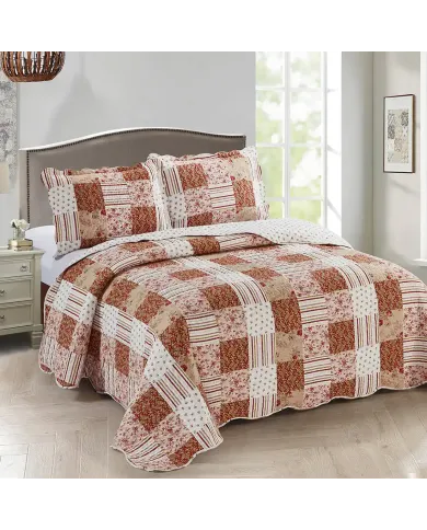 Een gezellige slaapkamer met een patchwork roze bedsprei in bloemen- en paisleyprints.