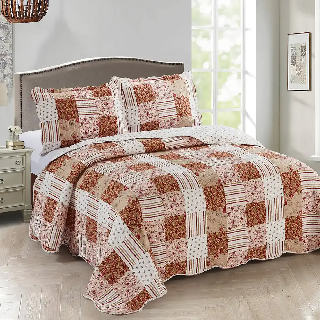 Een gezellige slaapkamer met een patchwork roze bedsprei in bloemen- en paisleyprints.