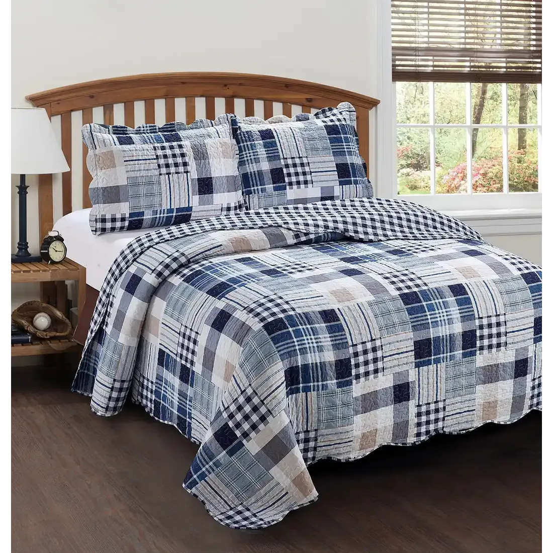 Een patchwork blauwe bedsprei met wit en beige tinten op een bed met bijpassende kussens.