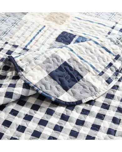 Close-up of a blue quilt, showcasing blue and white patchwork with a delicate stitching texture.