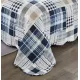 Detail van een blauwe bedsprei met blauw en wit patchwork, vermicellistiksels en geschulpte randen.