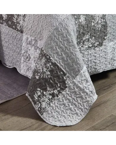 Detail of a grey quilt showcasing floral toile pattern, vermicelli stitching and scalloped edging.