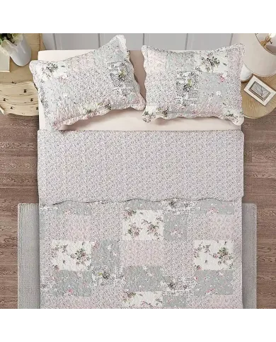 Top view of a floral patchwork quilt on a bed, complemented by matching decorative pillows.