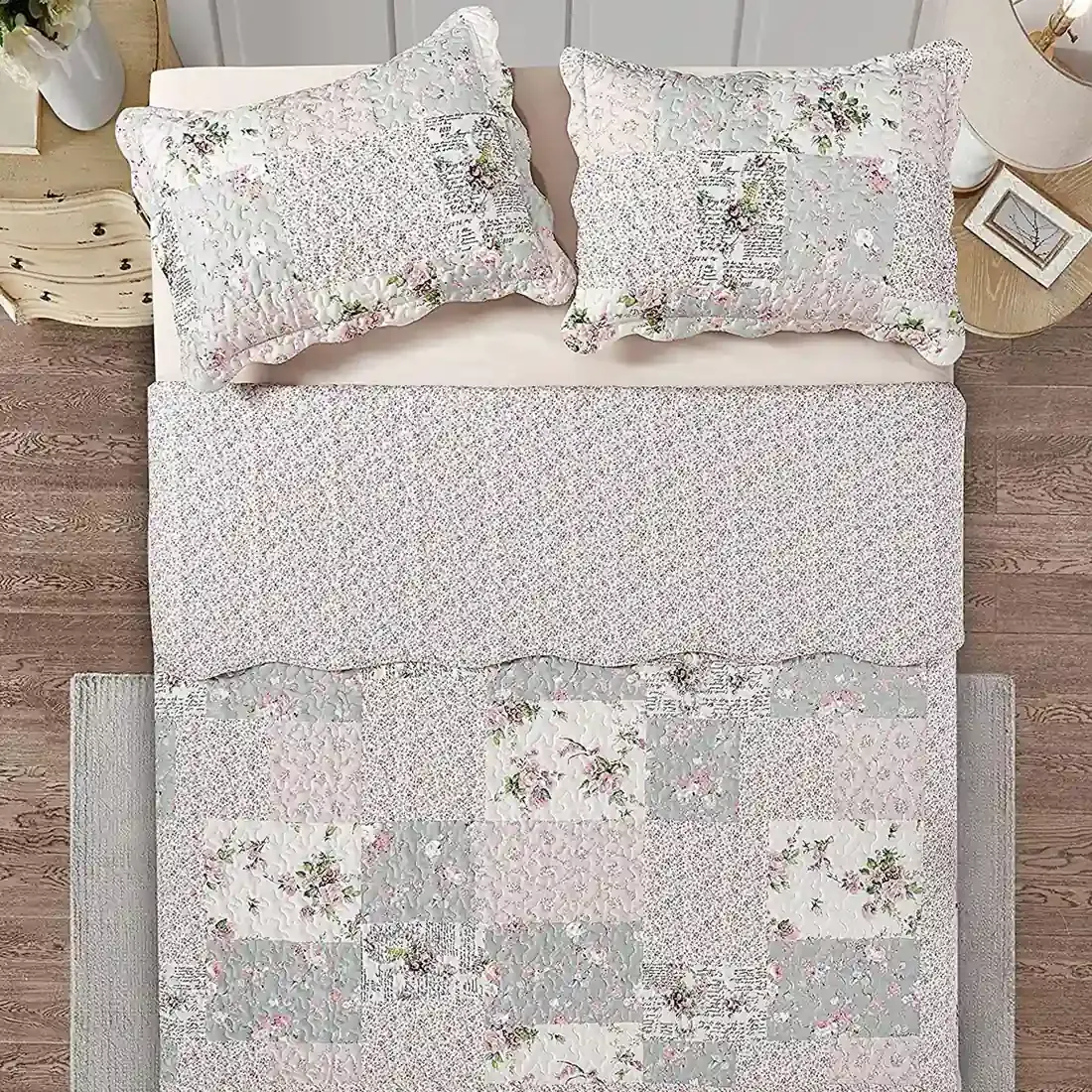 Top view of a floral patchwork quilt on a bed, complemented by matching decorative pillows.