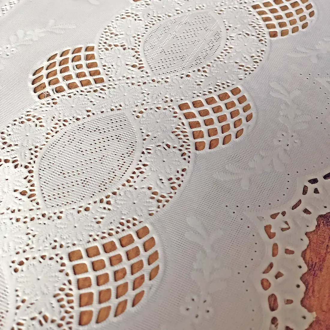 Close up detail of a white table runner made from vinyl with lace details.